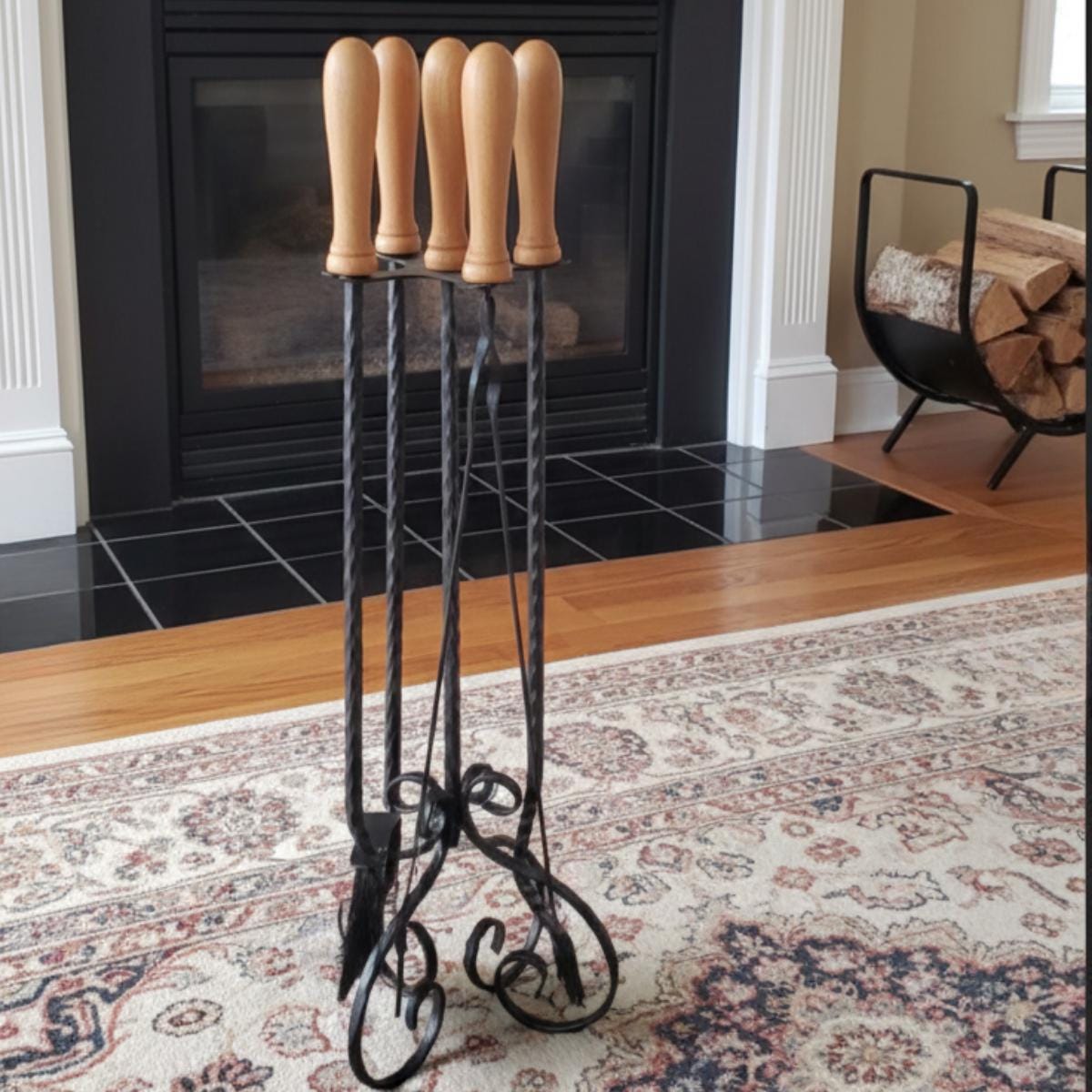 Fireplace tool set wrought iron with wood handles placed near indoor fireplace