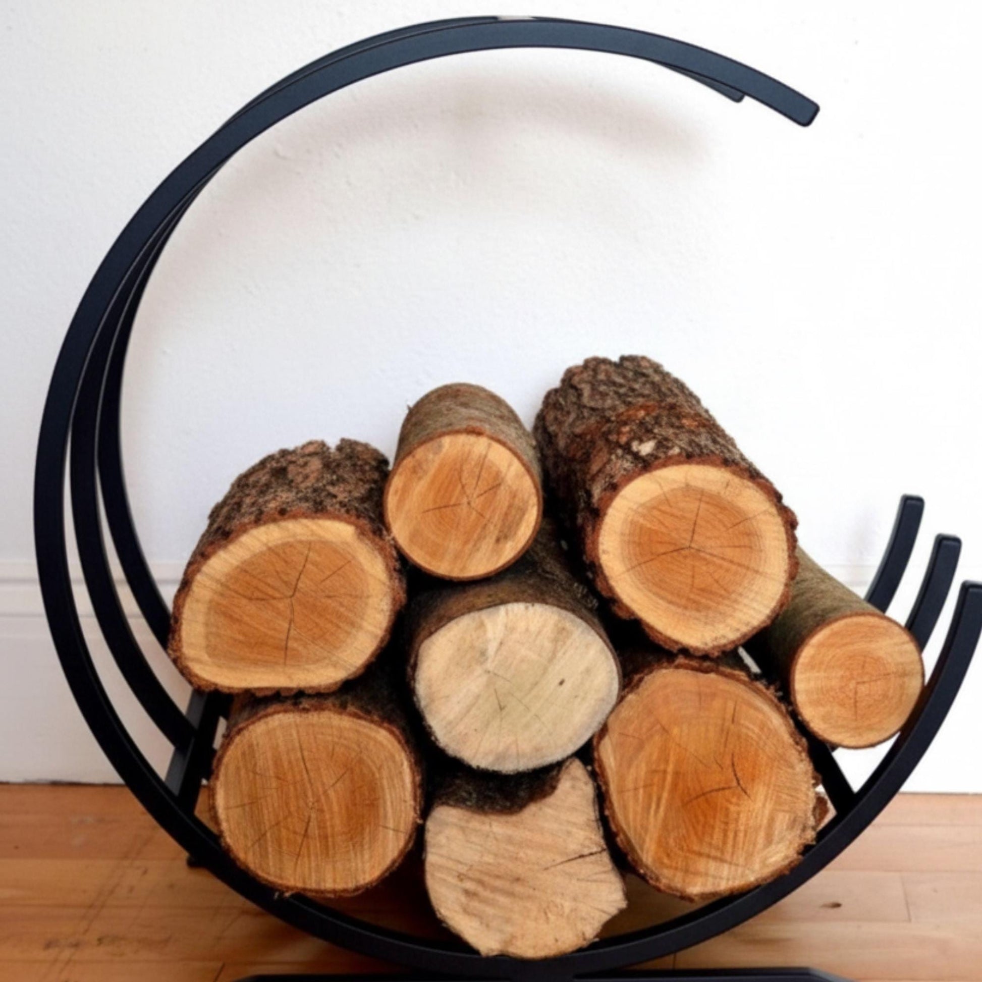 Modern curved firewood rack black metal indoor log holder, minimalist round firewood storage for fireplace, freestanding steel log rack for living room décor, durable powder coated firewood organizer for indoor wood storage